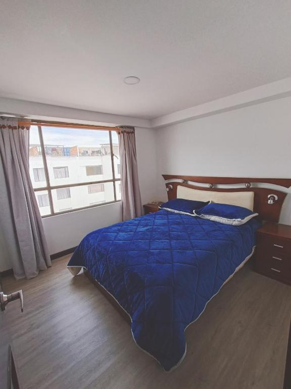 a bedroom with a blue bed and a large window at Apartamento moderno en condominio Agualongo in Pasto