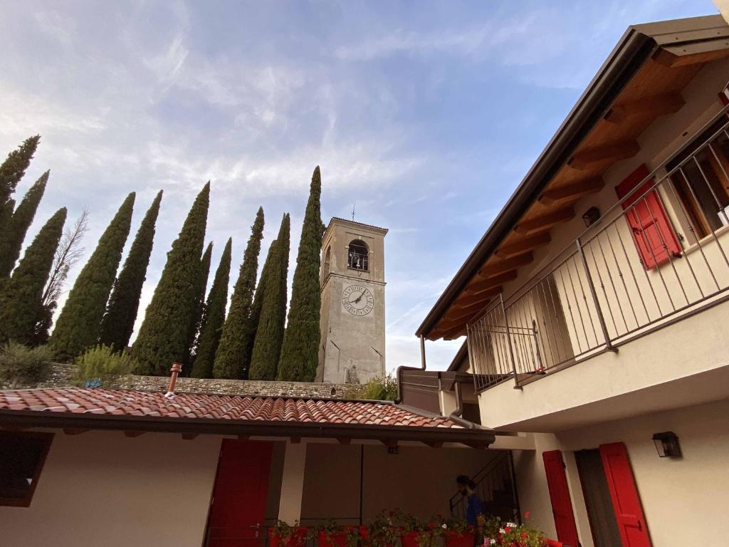 a building with a clock tower in front of trees at La Volpe Rossa Rooms and Apartments in San Felice del Benaco