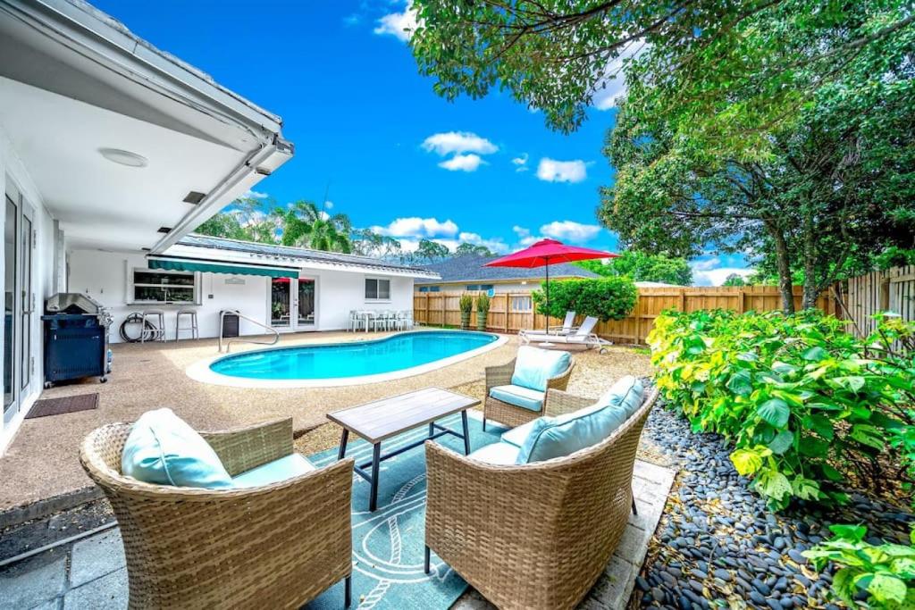 a backyard with a pool and chairs and a table at The Dreamcatcher - 4 Bed, 2 Bath, Private Heated Pool, BBQ, Game Room, Park in Fort Lauderdale