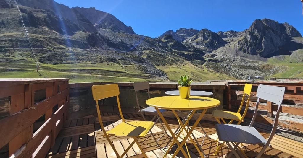 une table et des chaises jaunes sur une terrasse avec des montagnes dans l'établissement Studio La Mongie - Tourmalet au pied des pistes, à La Mongie