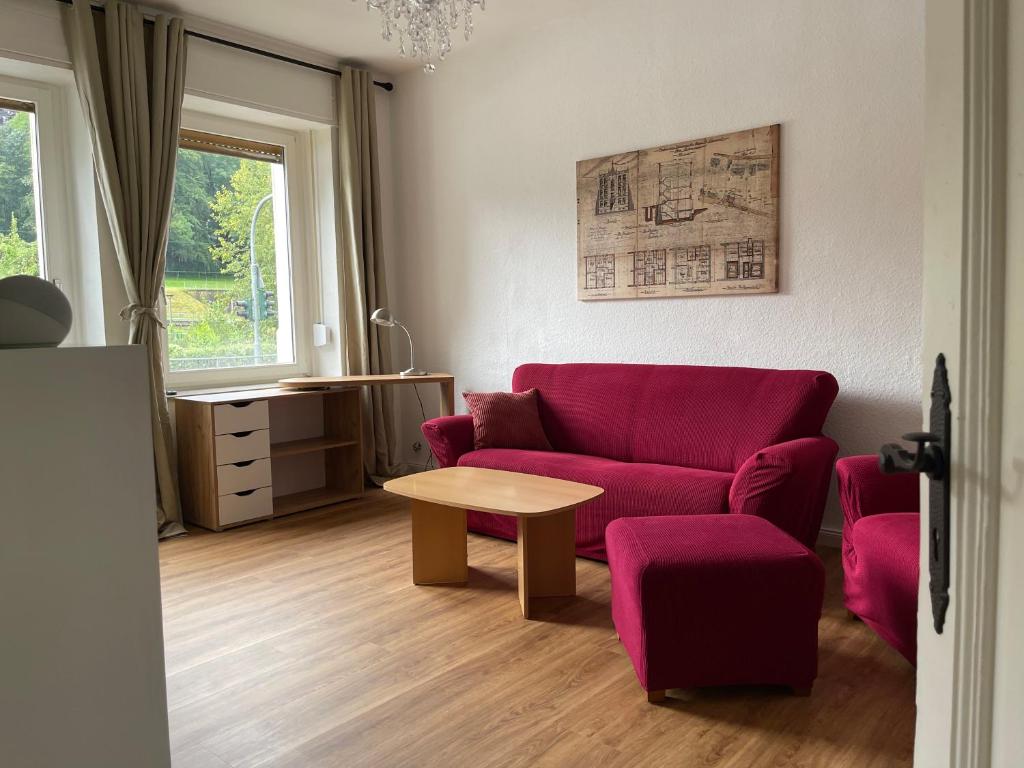 a living room with a red couch and a table at Wohnen am Wanderbahnhof Iserlohn in Iserlohn