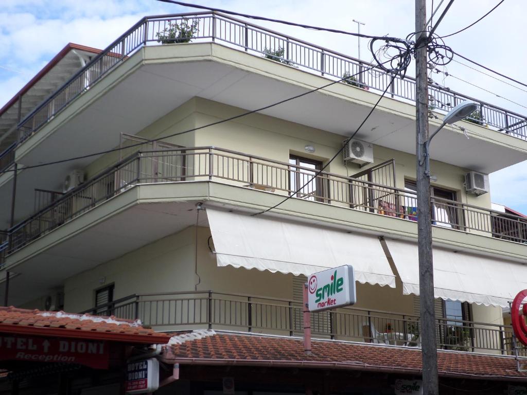 un grande edificio bianco con balcone e insegna vendita di Villa Nikolas a Paralia Katerinis
