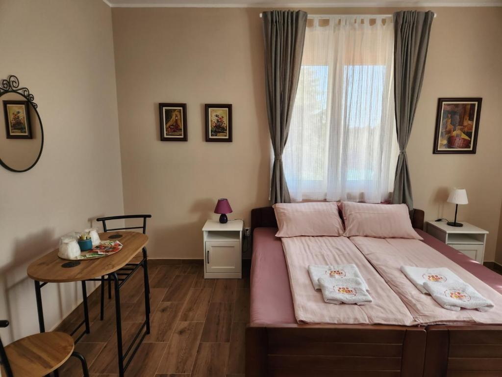 a bedroom with a bed and a table and a window at RoomsApartments PopCOURT in Pančevo