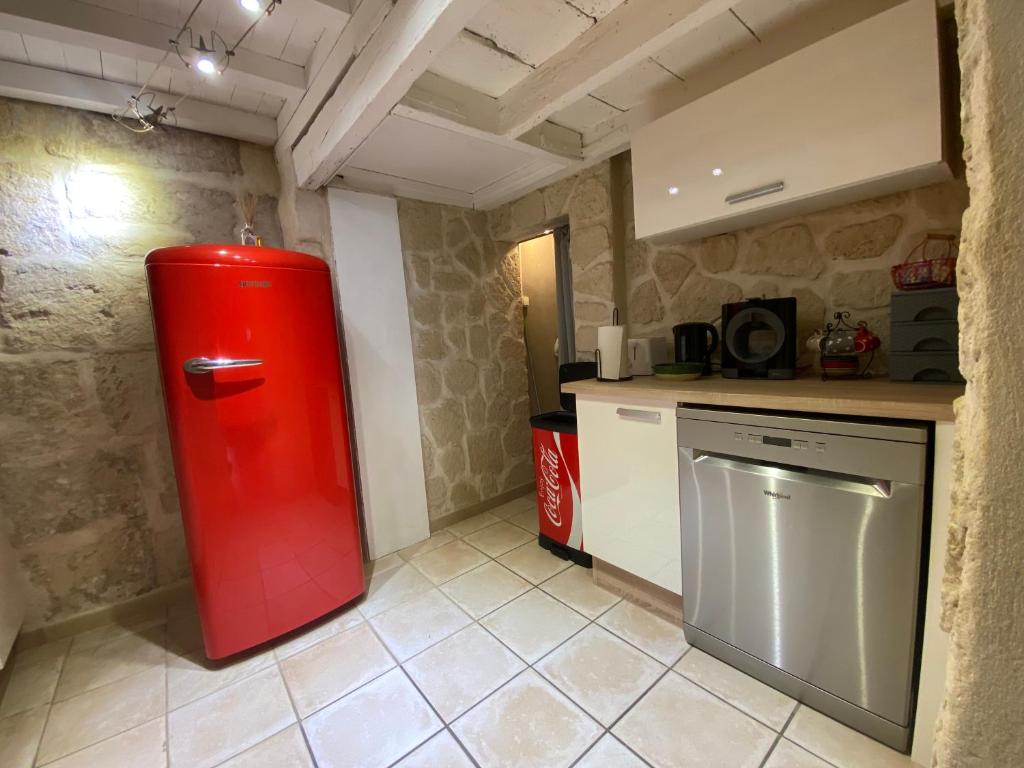 a kitchen with a red refrigerator in a room at Bienvenue au 6 - Calme et charme de la pierre. in Fourques