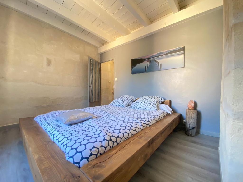 a bedroom with a large bed with a wooden frame at Bienvenue au 6 - Calme et charme de la pierre. in Fourques