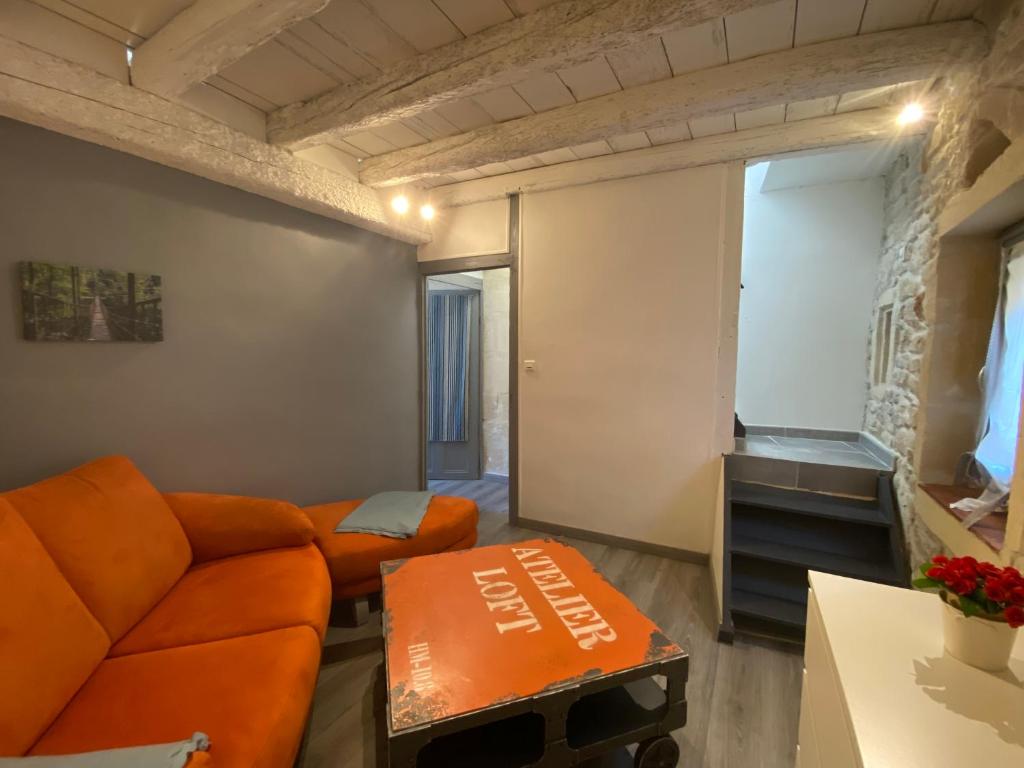 a living room with an orange couch and a tv at Bienvenue au 6 - Calme et charme de la pierre. in Fourques