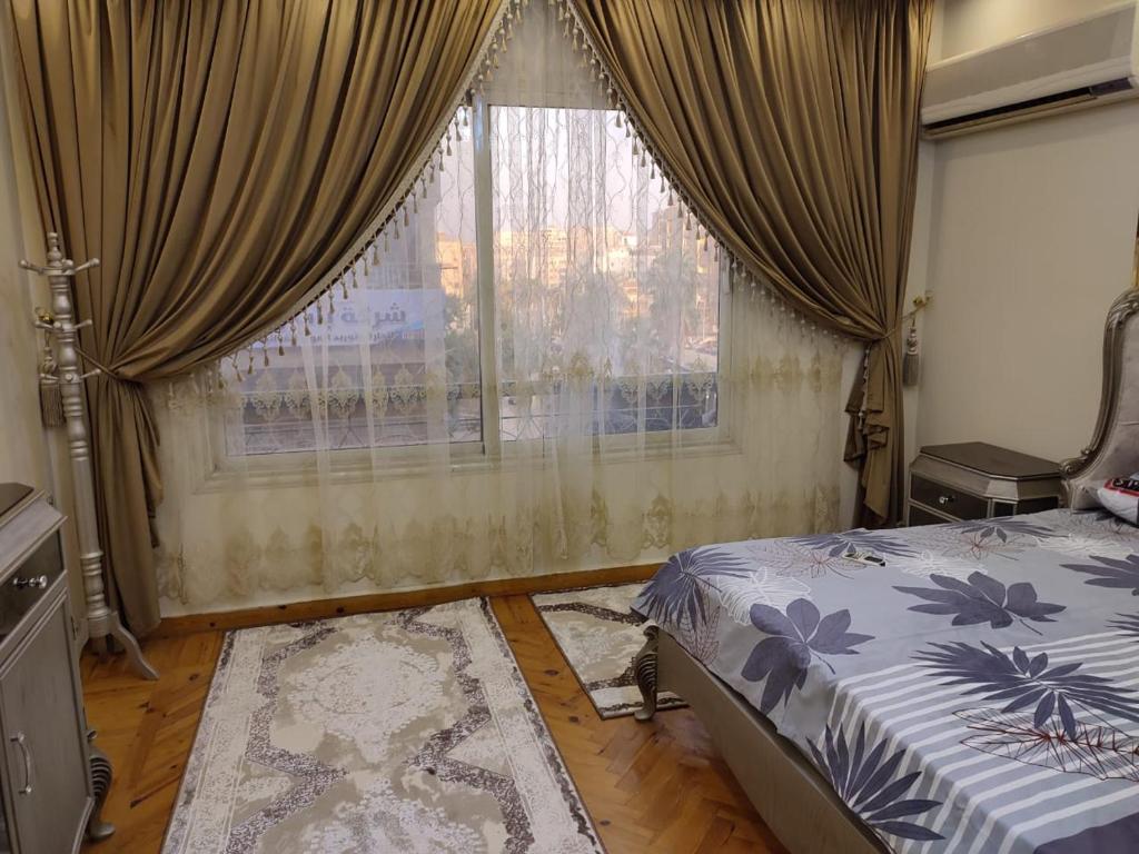 a bedroom with a bed and a window with curtains at Haram Street Apartment Best Vacation Group in Cairo