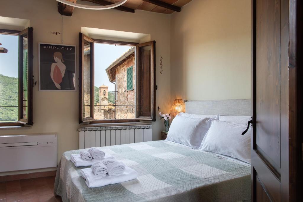 a bedroom with a bed with towels on it at Il Borghetto - La Ghibellina Townhouse in Castelnuovo dellʼAbate