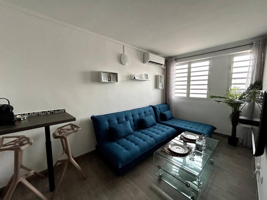 een woonkamer met een blauwe bank en een tafel bij Appartement 42 in Fort-de-France