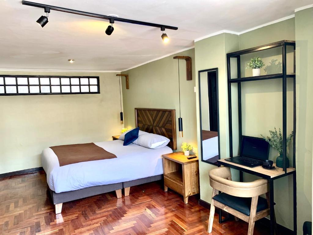 Un dormitorio con una cama y un escritorio con una computadora. en Apartamentos Montes, en Cusco