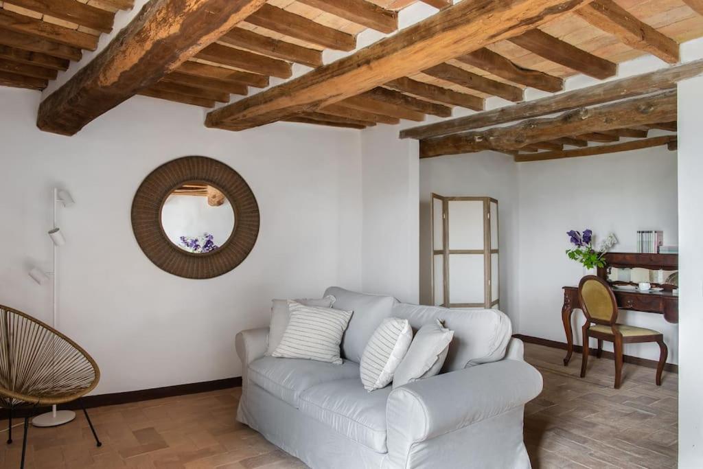 ein Wohnzimmer mit einem weißen Sofa und einem Spiegel in der Unterkunft Il Borghetto - La Casa di Elba, Terrazzo panoramico in Val d'Orcia in Castelnuovo dellʼAbate
