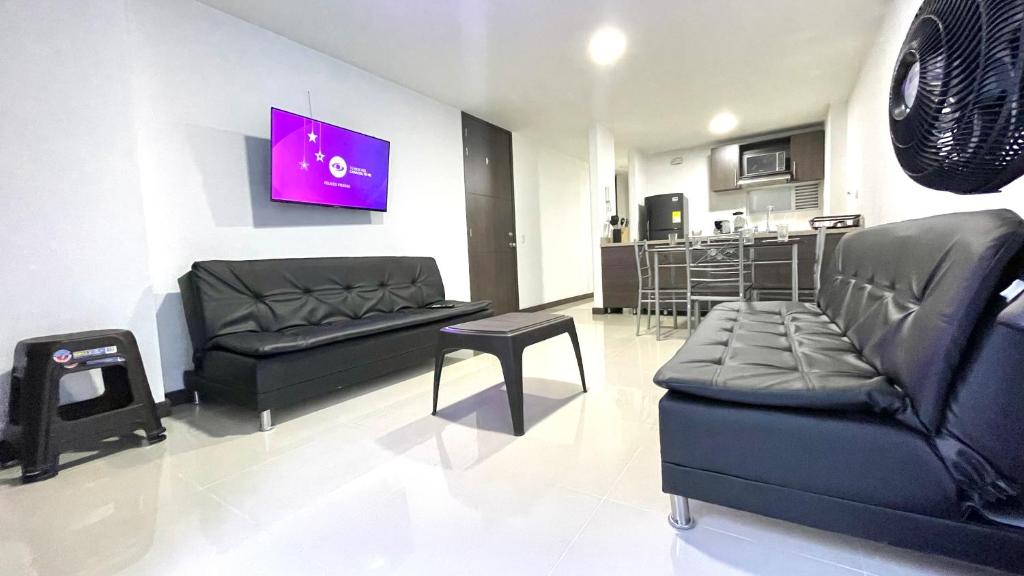 sala de estar con muebles de cuero negro y cocina en Apartamento moderno en conquistadotes, excelente ubicación., en Medellín