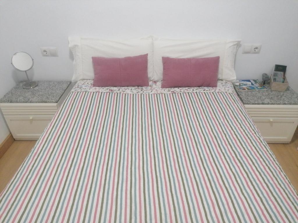 Una cama con dos almohadas moradas encima. en El descanso en Mairena del Aljarafe