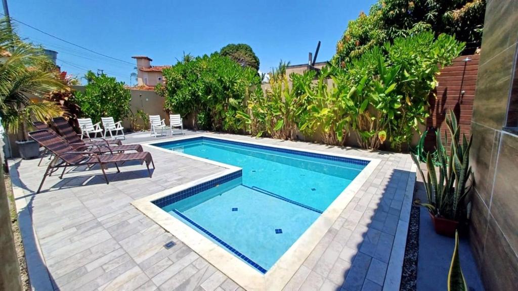 a small swimming pool in a patio with chairs and trees at Casa confortável tudo para seu bem-estar. in Porto Seguro