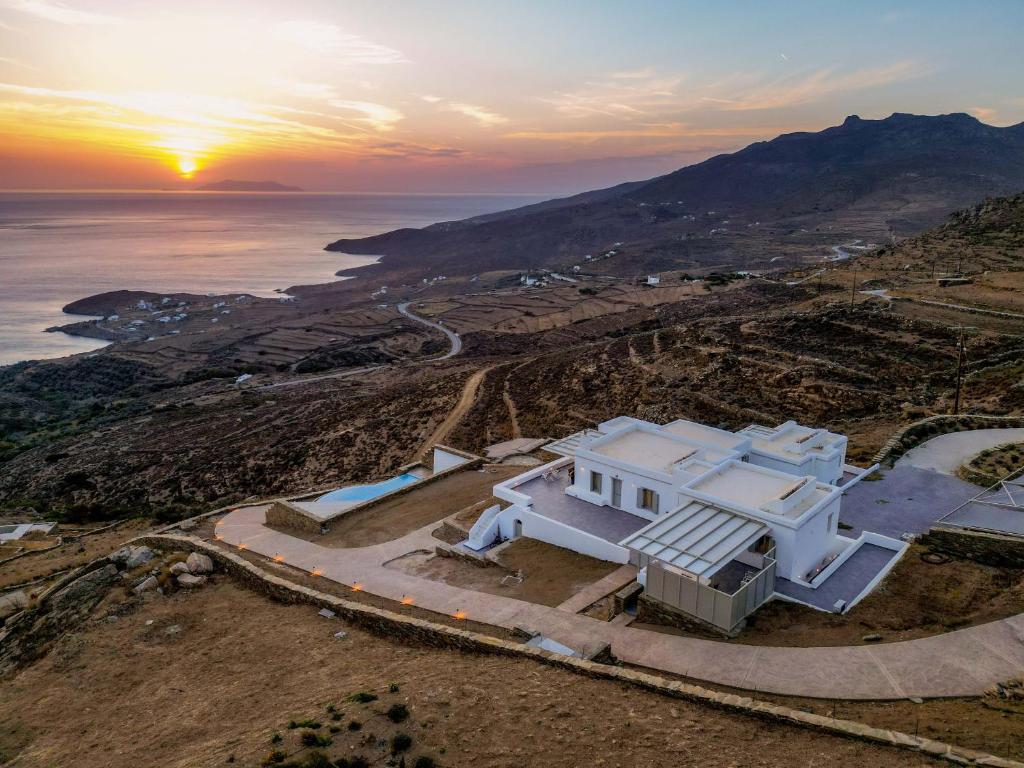 une maison sur une colline avec le coucher du soleil en arrière-plan dans l'établissement Alos Residence, à Agios Romanos