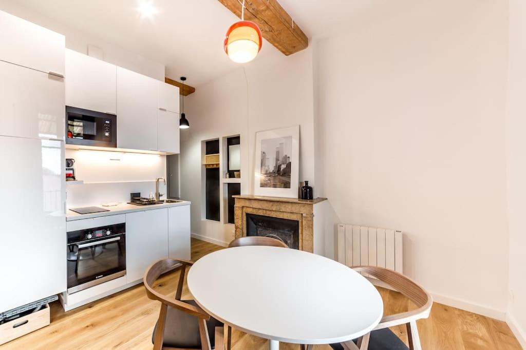 a kitchen with a white table and chairs in a room at Grand T2 avec balcon • proche parc de la Tête d'Or in Caluire-et-Cuire