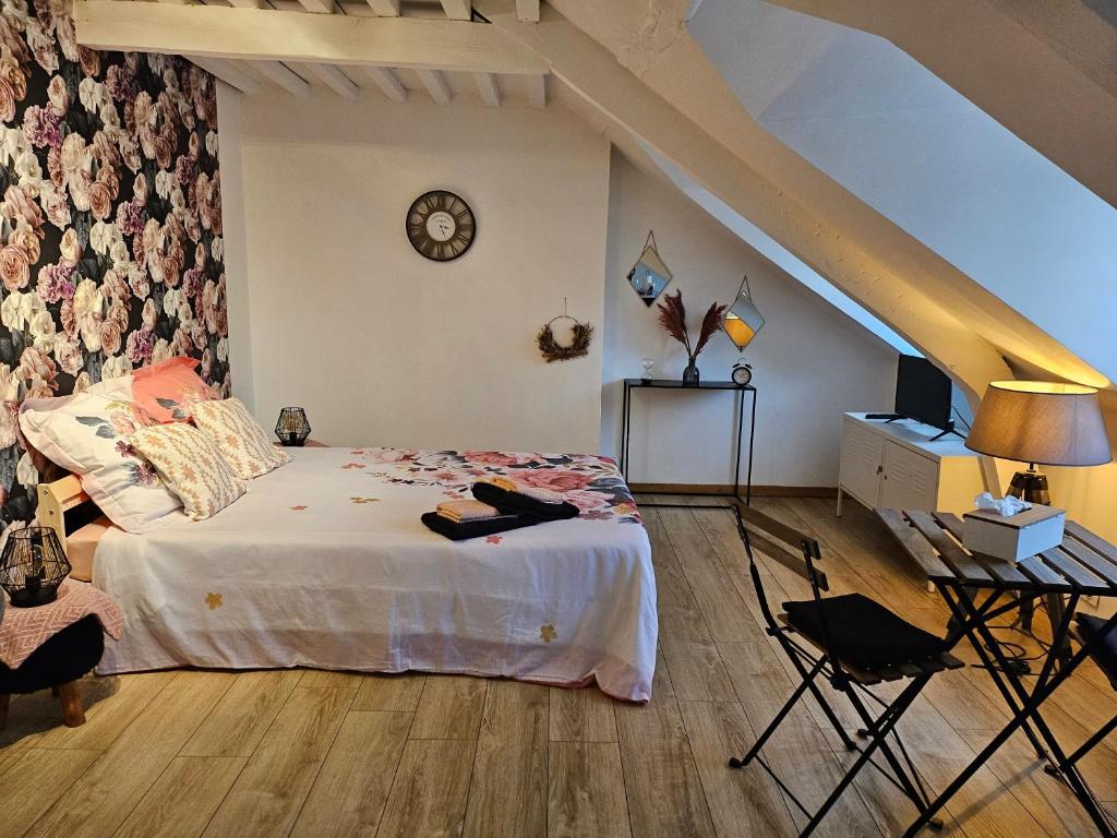 - une chambre avec un lit, une table et une horloge dans l'établissement La panthère rose, à Honfleur