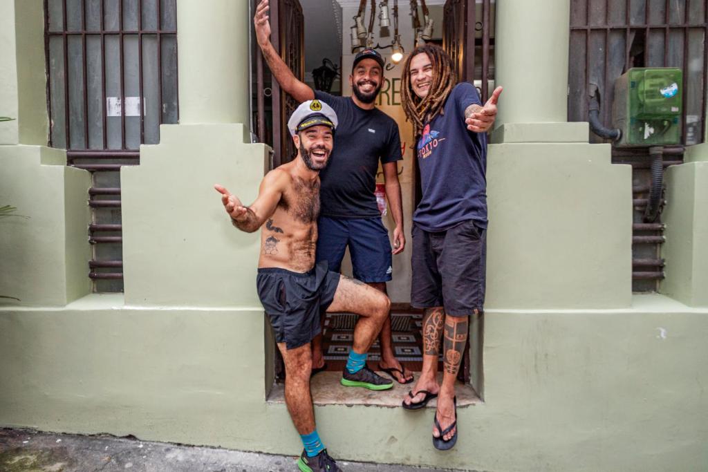 un groupe de trois hommes debout à l'extérieur d'un bâtiment dans l'établissement Books Hostel, à Rio de Janeiro