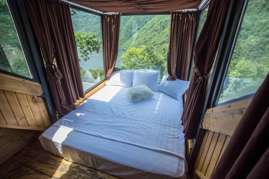 a bed in a room with a large window at Woodpecker Georgia in Batumi