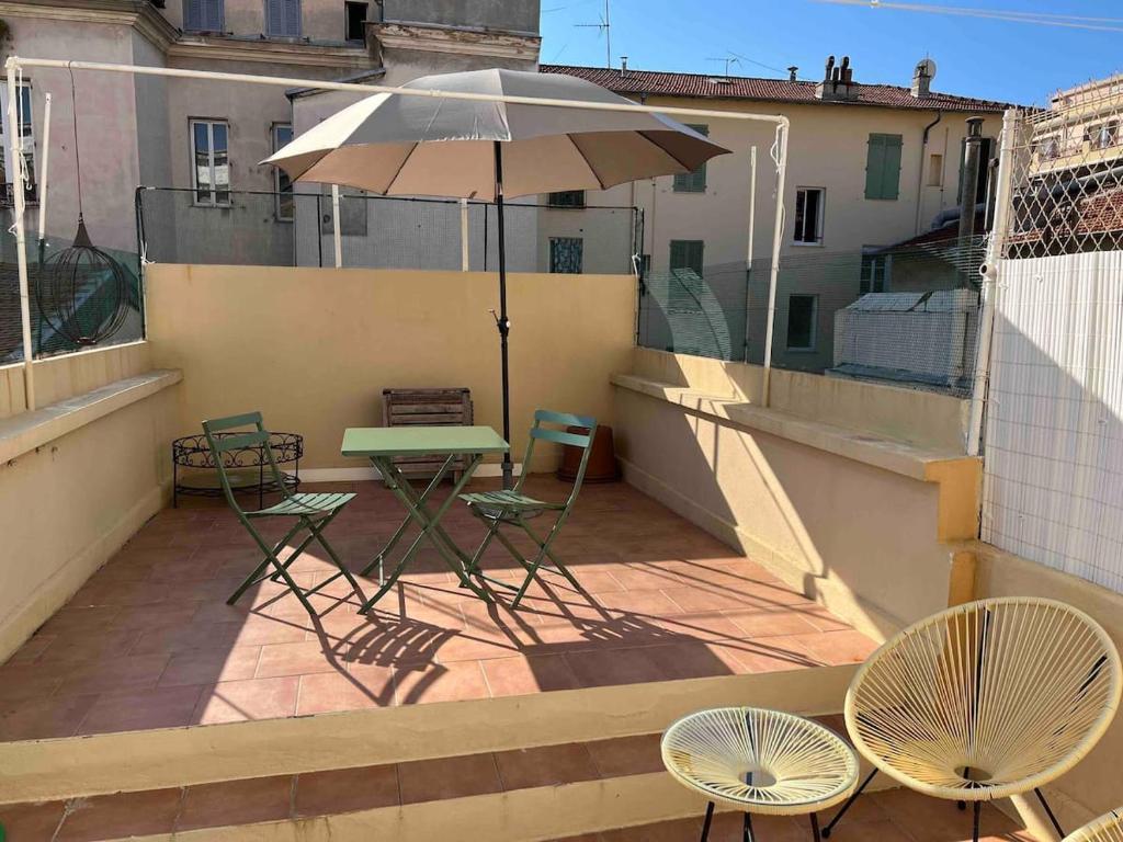 un balcon avec une table, des chaises et un parasol dans l'établissement AMAZING STUDIO - GRANDE TERRASSE - COEUR DE VILLE - WIFI - AC, à Nice