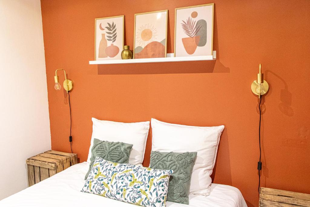 a bedroom with orange walls and a bed with pillows at Nîmes Centre - A 5 minutes des Arènes in Nîmes