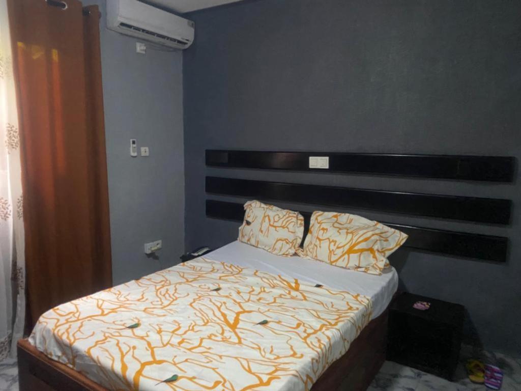sypialnia z łóżkiem z drewnianym zagłówkiem w obiekcie Sunrise Center Bonapriso 104 w mieście Duala
