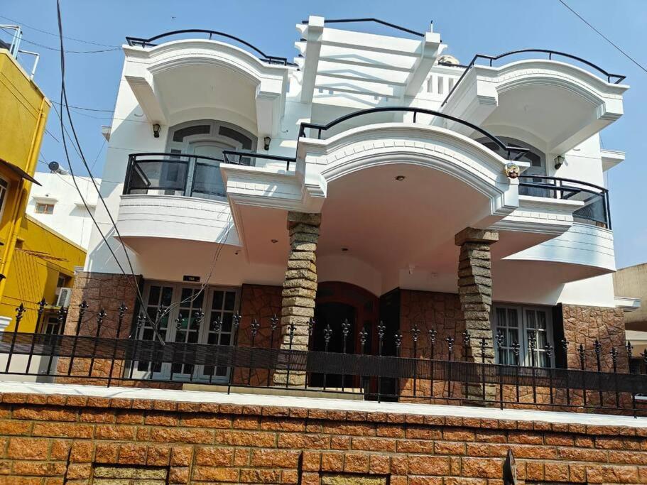 a large white house with a fence in front of it at Waterfall Villa - 4BHK in Mysore