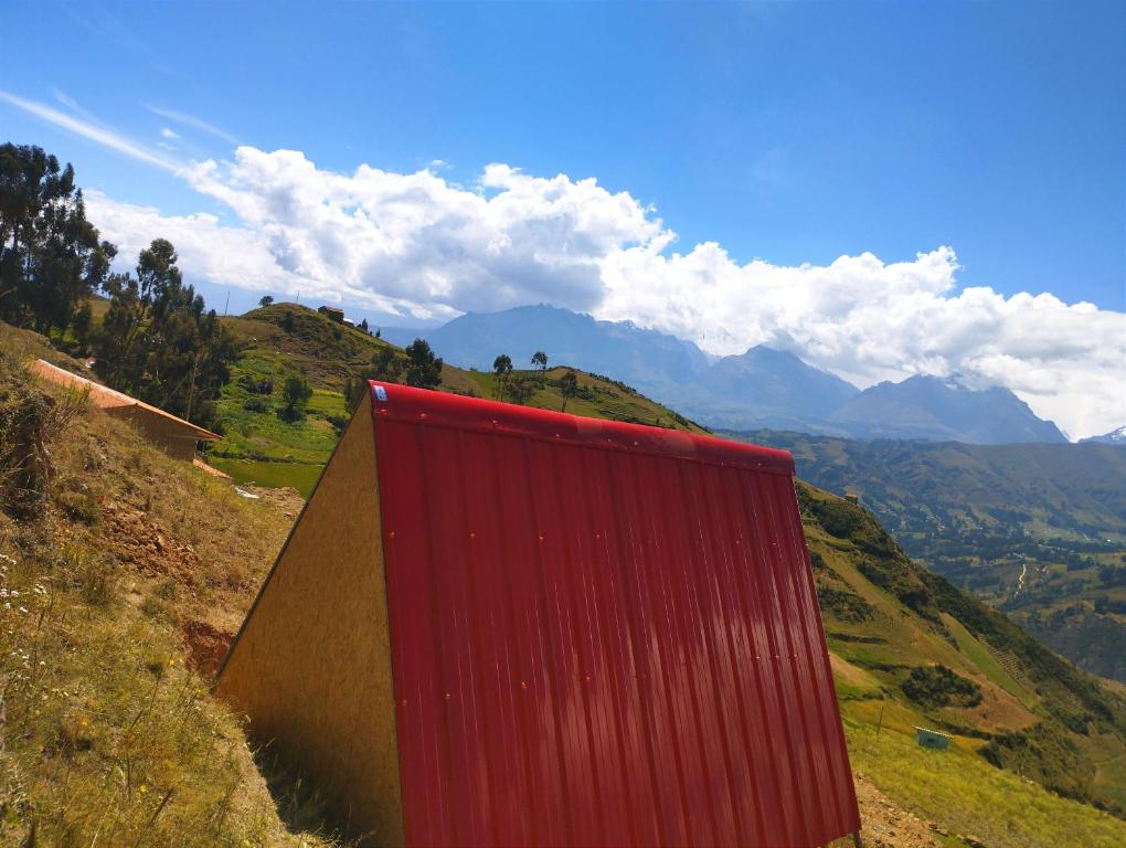 a red building on the side of a mountain at mountain view willcacocha lodge in Huaraz