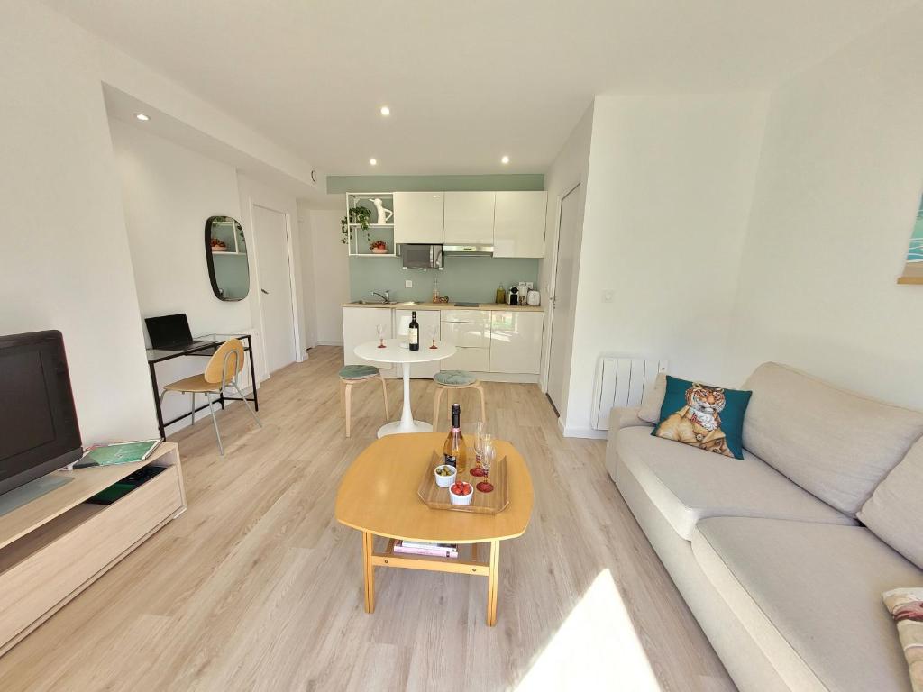 uma sala de estar com um sofá e uma mesa em Paisible, spacieux avec petit jardin em Artigues-près-Bordeaux