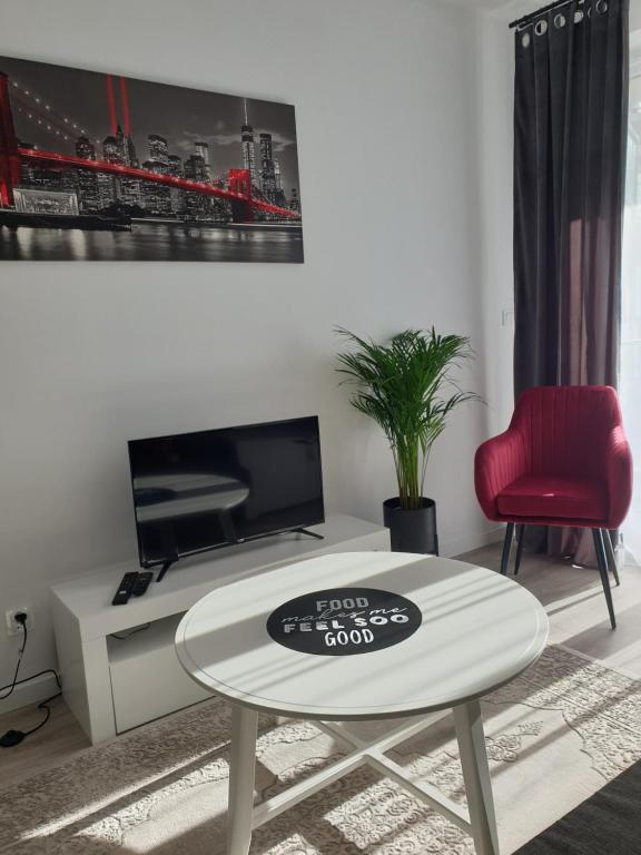 ein Wohnzimmer mit einem weißen Tisch und einem roten Stuhl in der Unterkunft Apartamenty POSNANIA - MALTA , Faktura VAT, bezkontaktowe zameldowanie, bezpłatne miejsce parkingowe in Posen