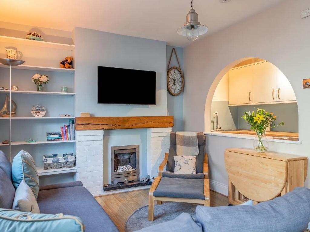 a living room with a fireplace and a tv at Seas the Day Cottage, Dartmouth in Dartmouth