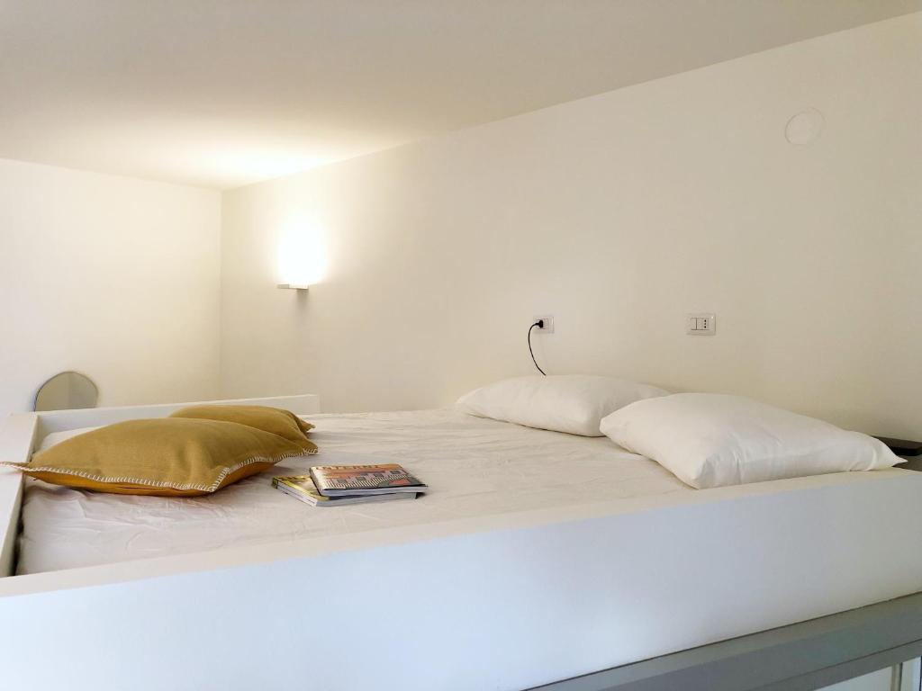 een wit bed met twee kussens en een boek erop bij City Center Apartment Piacenza in Piacenza
