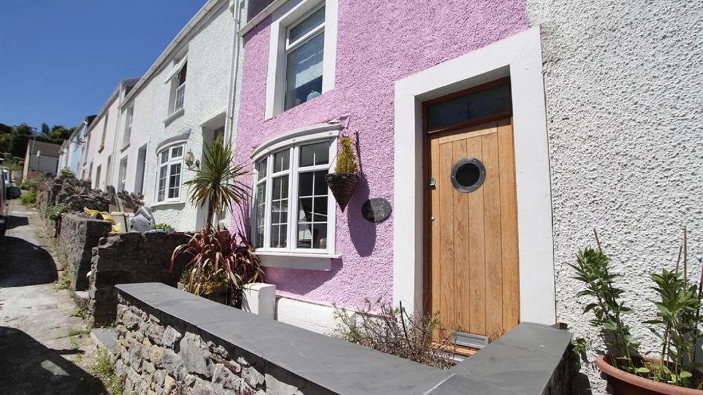 a pink house with a wooden door on a street at Tichbourne Street, Mumbles in The Mumbles