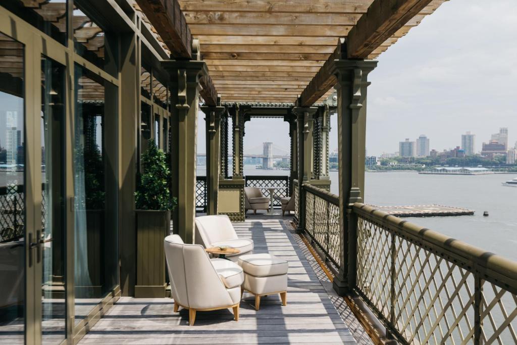 une véranda avec des chaises et une table et une vue sur l'eau dans l'établissement Casa Cipriani New York, à New York