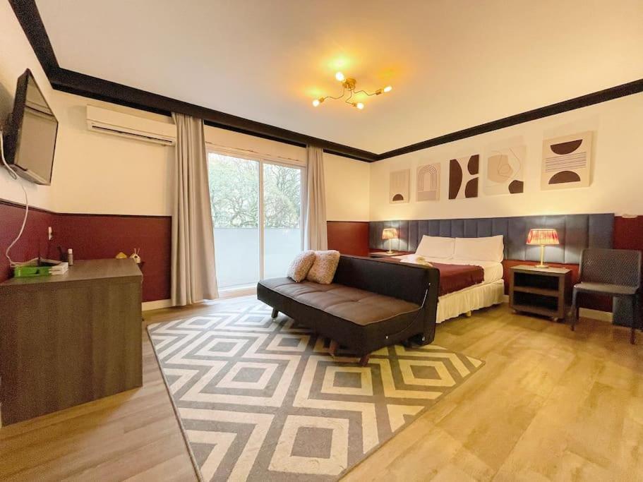 a bedroom with a bed and a couch and a television at Studio Duque Classic in Porto Alegre