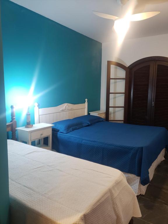 a bedroom with two beds and a blue wall at Casa Praia Jd Acapulco in Guarujá