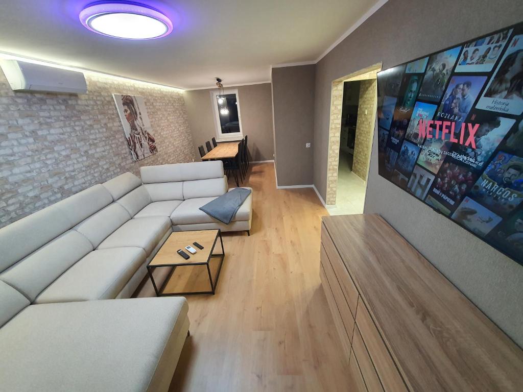 ein Wohnzimmer mit einem weißen Sofa und einem TV in der Unterkunft JDK Apartamenty Legionów 74m2 8-osobowy in Kalisz