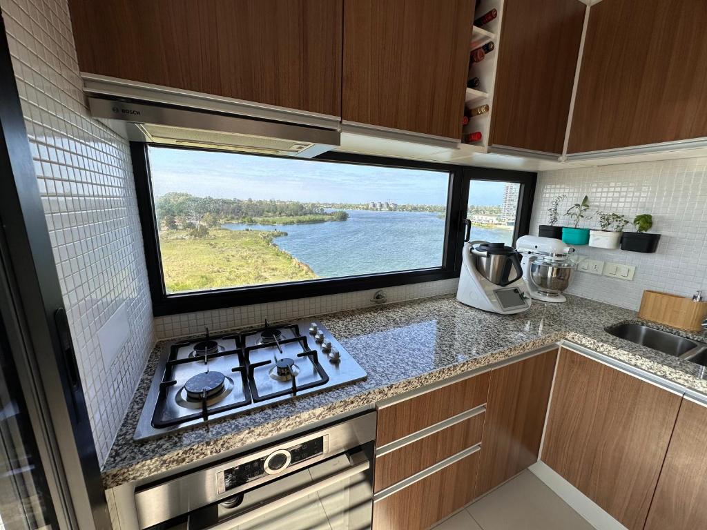 a kitchen with a stove and a large window at Apartamento frente al lago in Montevideo
