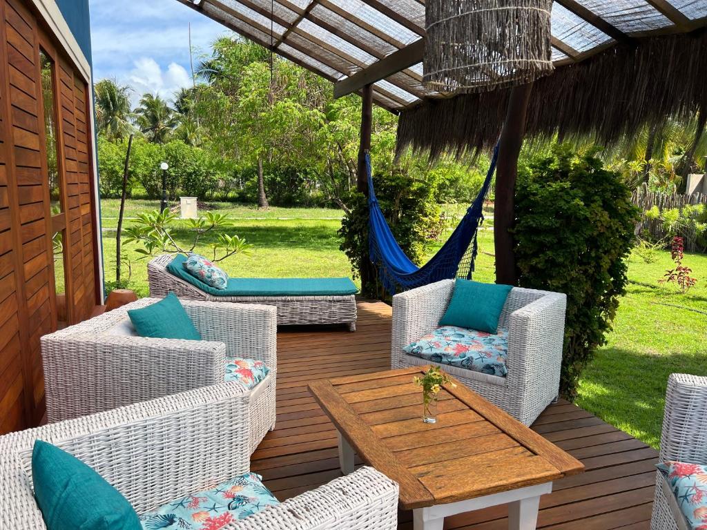 um pátio com cadeiras, uma mesa e uma rede de descanso em Casa Vagalume - 10 minutes to secluded beach em Pôrto de Pedras