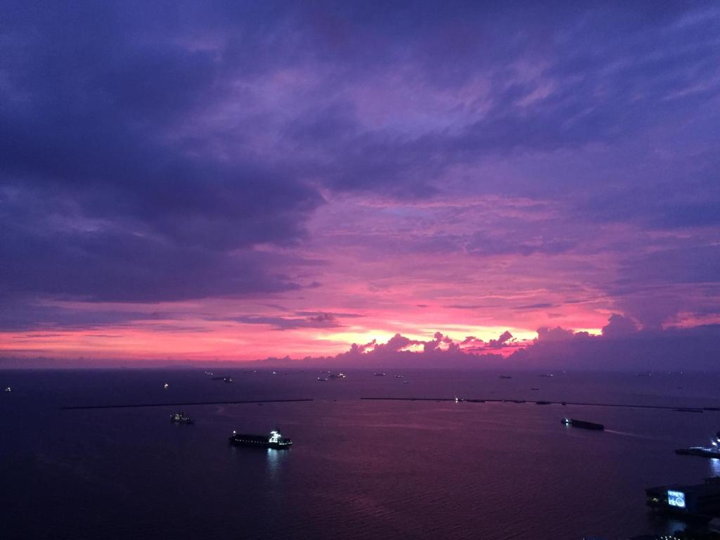 een zonsondergang over een groot water met boten bij Beachside Embassy Apartment in Manilla