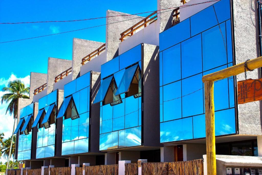 un bâtiment avec des fenêtres bleues sur son côté dans l'établissement Triplex Temporada Areia e Mar Patacho - Casa Verde, à Porto de Pedras