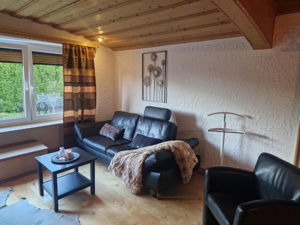 een woonkamer met een leren bank en een tafel bij Ferienwonung in Pullenreuth