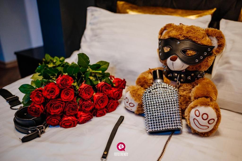 un oso de peluche con una máscara junto a un ramo de rosas en Apartament Pod Skrzydłami Aniola en Bytom