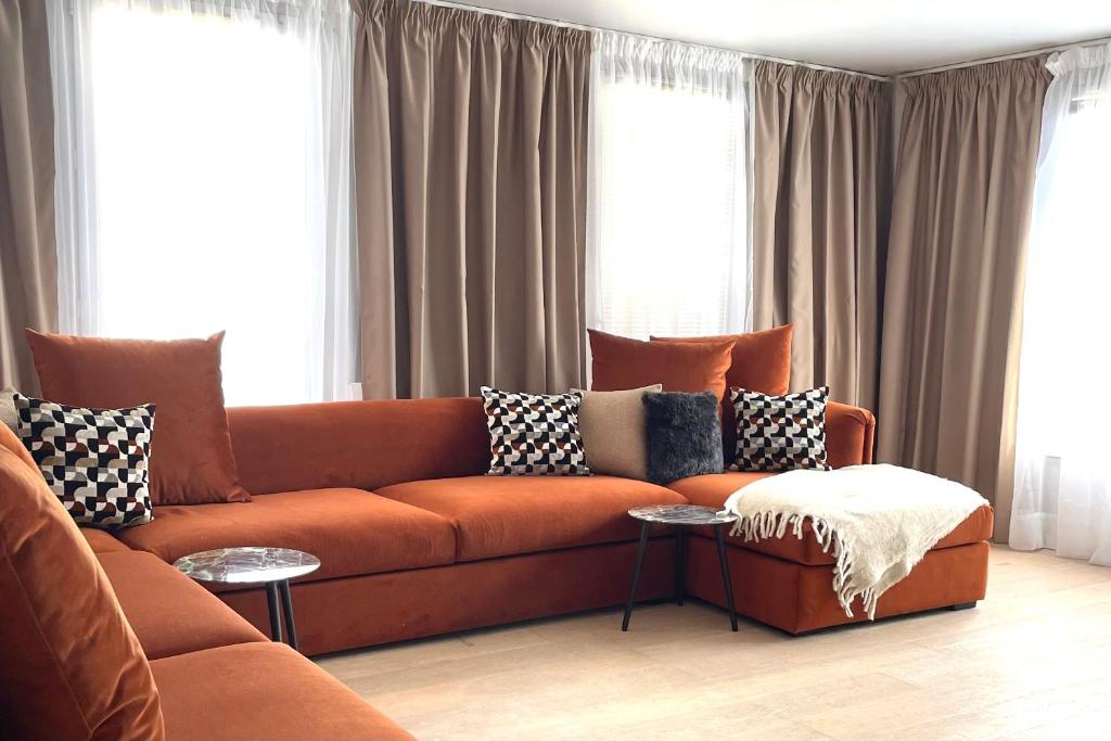 an orange couch in a living room with windows at Le Duplex Paris Basilique Stade de France in Saint-Denis