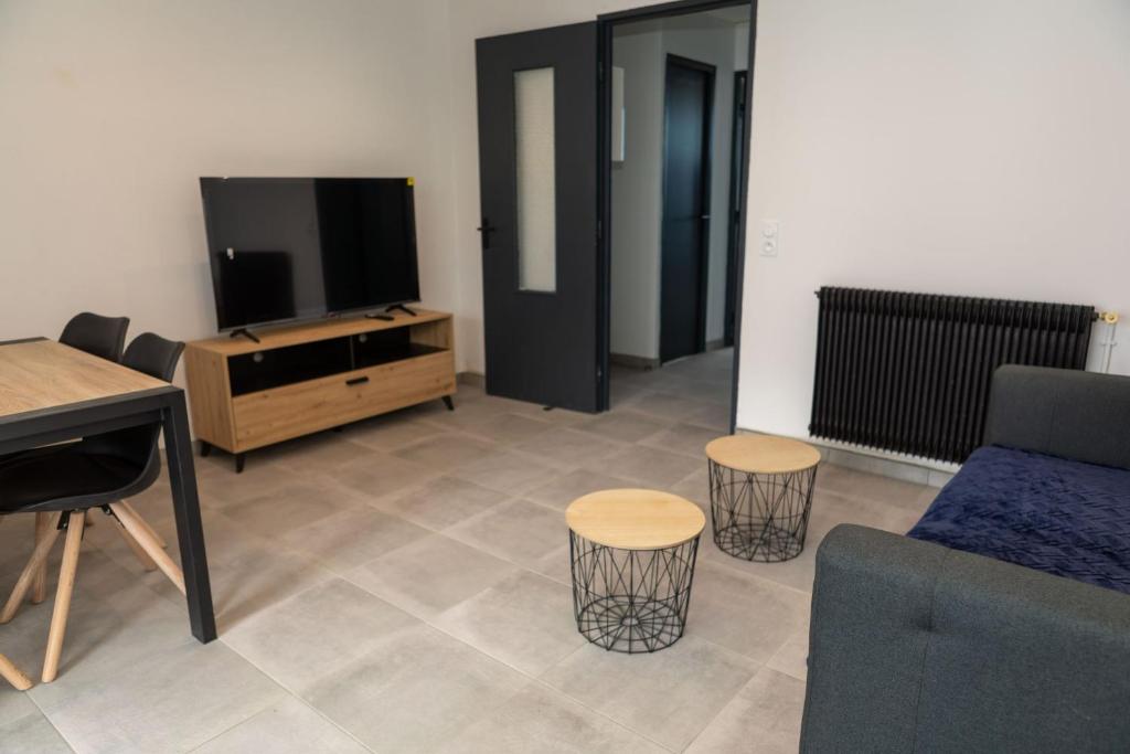 ein Wohnzimmer mit einem TV, einem Sofa und einem Stuhl in der Unterkunft A spacious nest for an unforgettable holiday in Perpignan