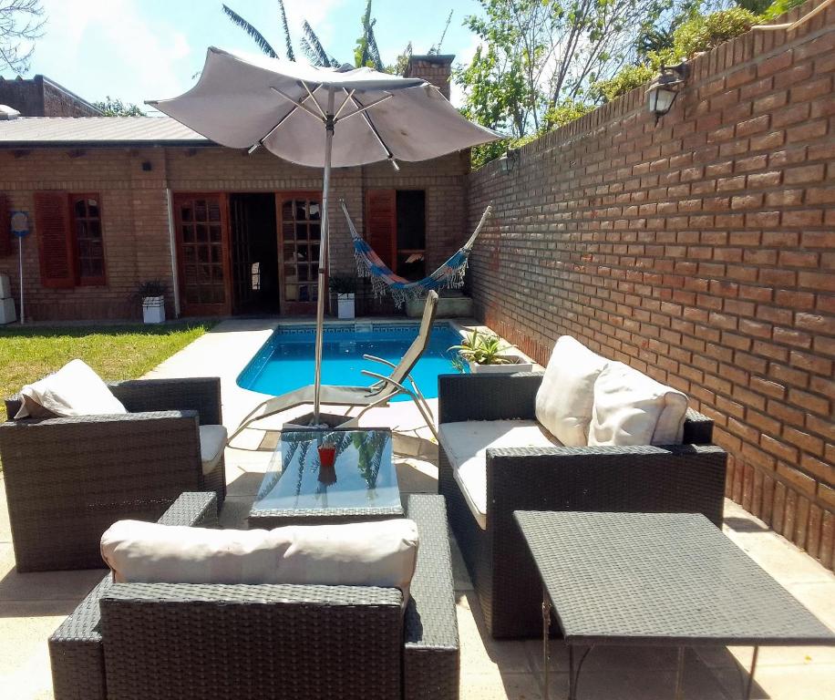 une terrasse avec des canapés, un parasol et une piscine dans l'établissement Alquiler temporario Santo Tome, à Santo Tomé