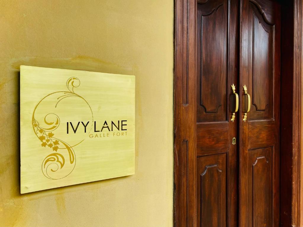 een bord op een muur naast een deur bij Ivy Lane Galle Fort in Galle