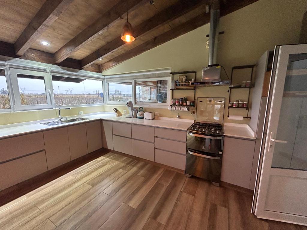 una cocina con armarios blancos y suelos y ventanas de madera. en Valle Andino Tempo en Trevelín