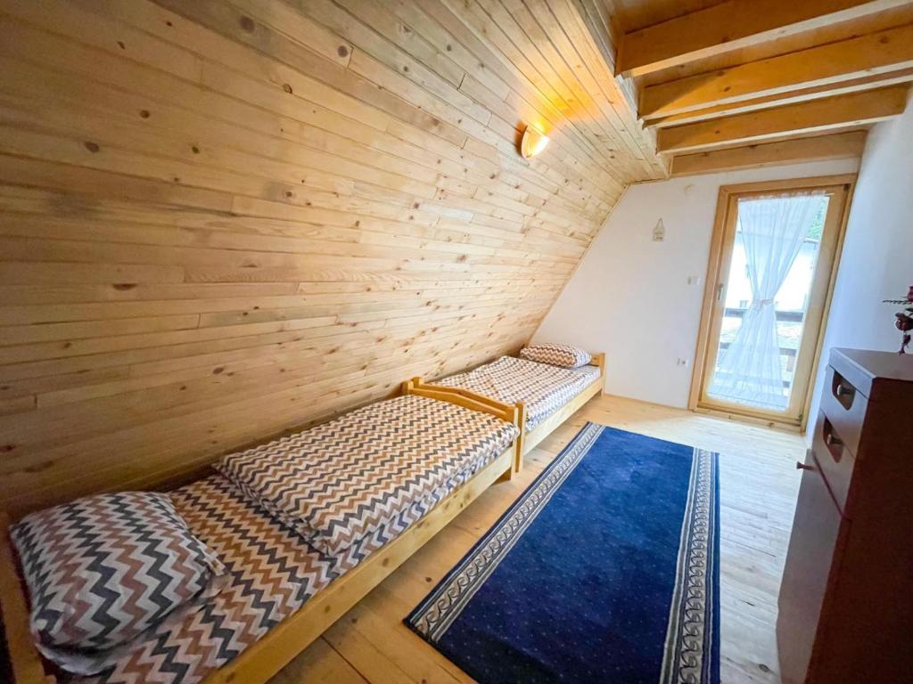 two beds in a room with a wooden wall at Holiday home Bella Vlašić in Šišava