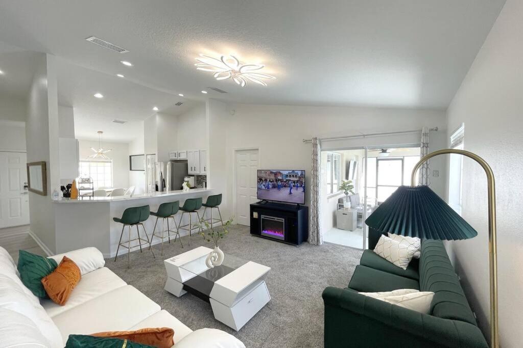sala de estar con sofá verde y cocina en Luxury Modern Pool House close to theme parks., en Kissimmee